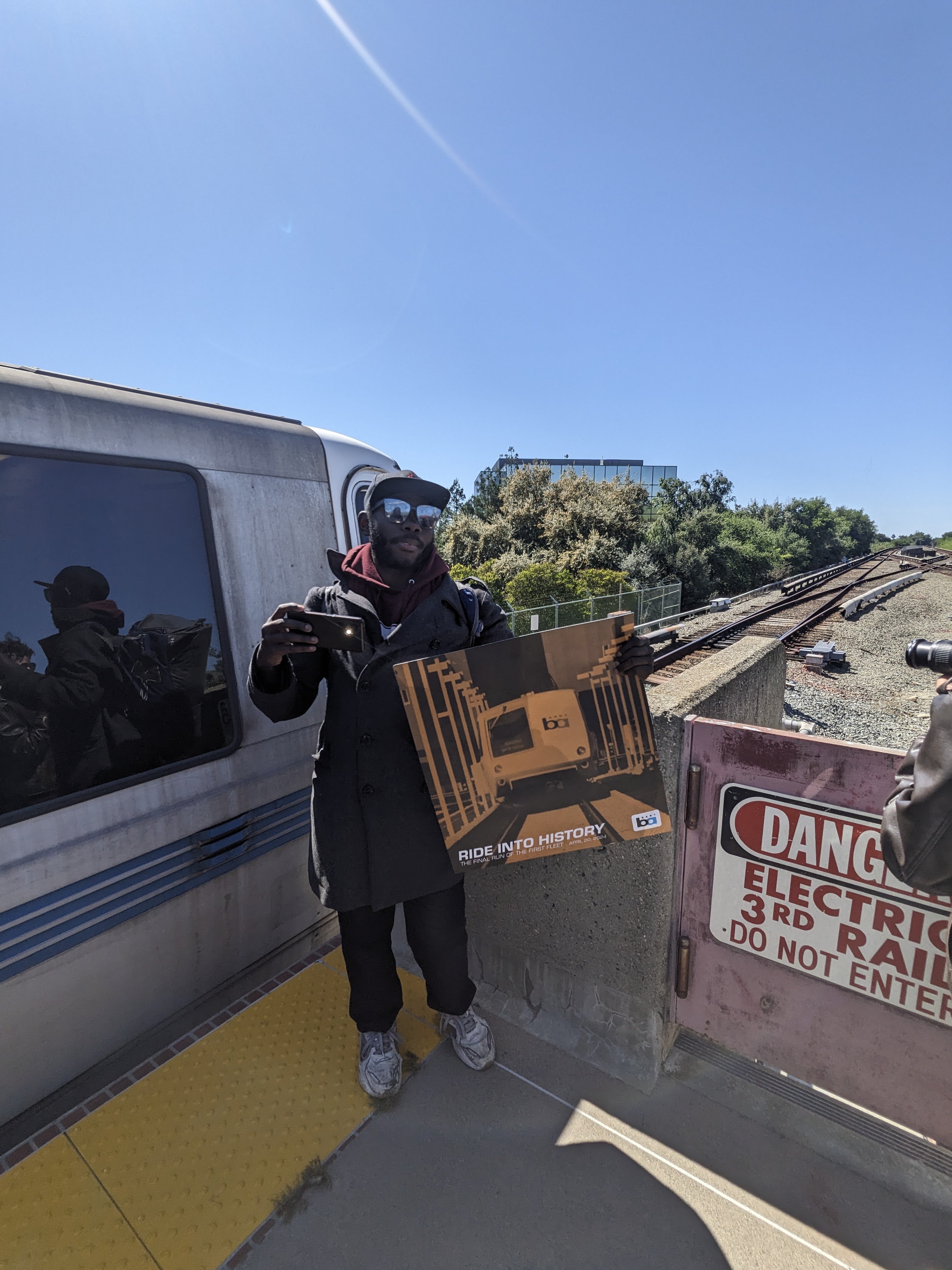 A man holding a final legacy train poster after the second-to-last train reached Fremont station